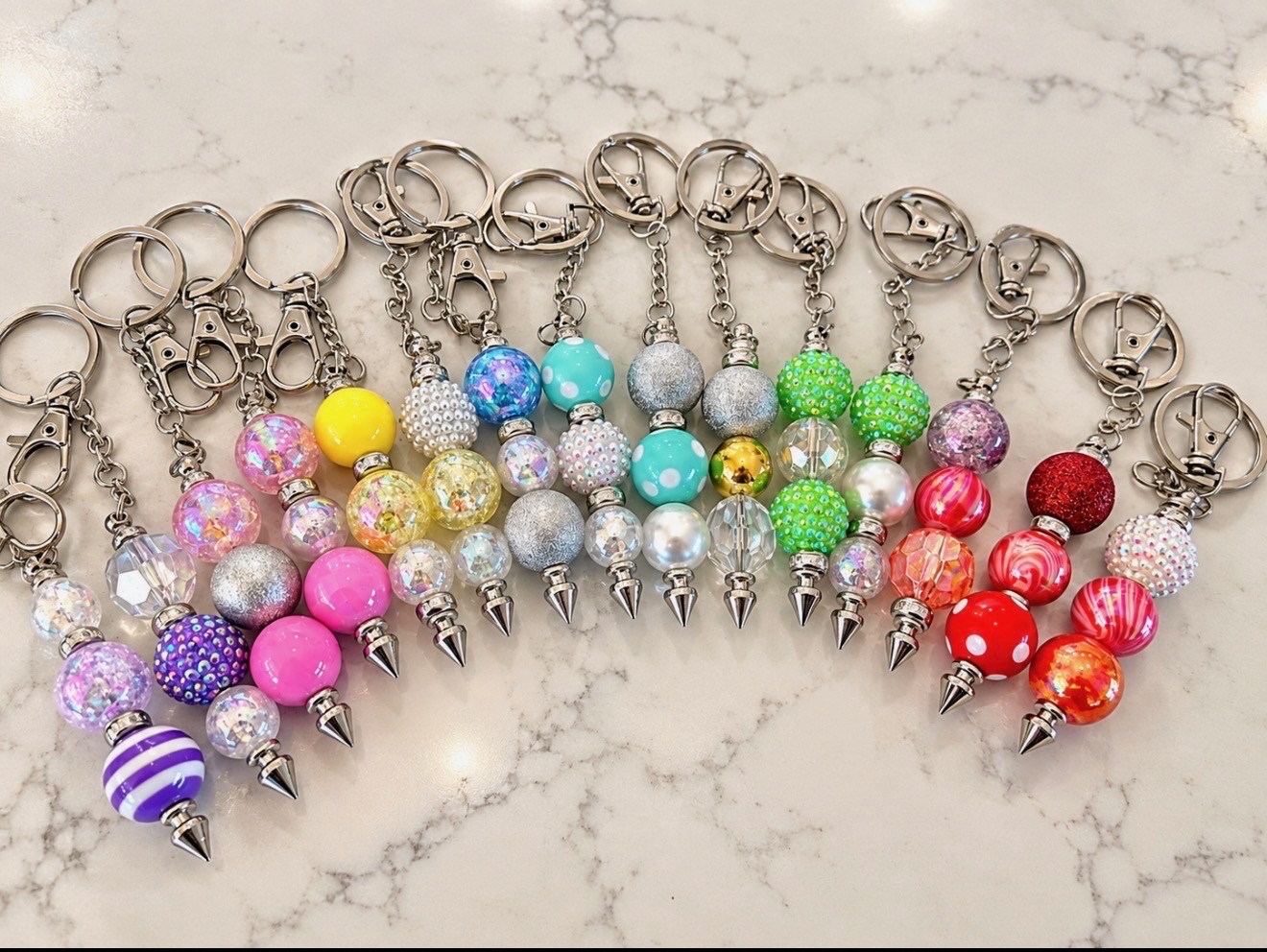 Handmade beaded keychains in a variety of bright colors, with rings and charms fully visible